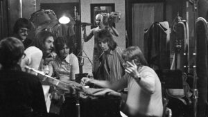 Tom Dowd, back to camera, Roger Hawkins, Steve Cropper, Pete Carr, Rod Steward and Barry Beckett work on an arrangement as Engineer Jerry Masters moves equipment in the background